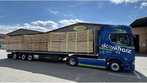 Bild zeigt einen vollbeladenen blauen LKW auf einer Lagerfläche. Im Hintergrund ist blauer Himmel mit Wolken zu sehen.