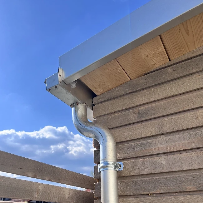 Bild zeigt einen Ausschnitt von einem Gartenschuppen mit moderner Holzfassade hochwertigem Windfang aus verzinktem Blech.