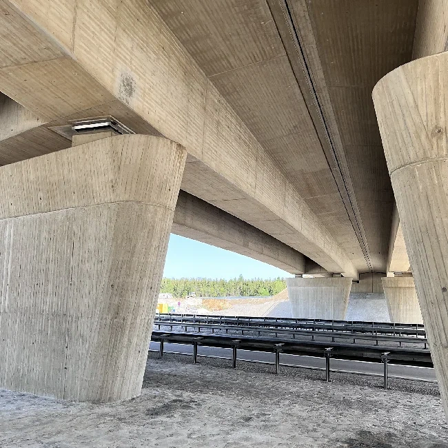 Bild zeigt eine moderne Autobahnbrücke mit massiven Säulen.