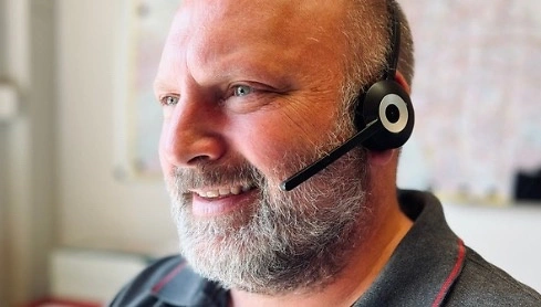 Mann mit Headset in einem Büro, arbeitet an der Handwerkervermittlung.